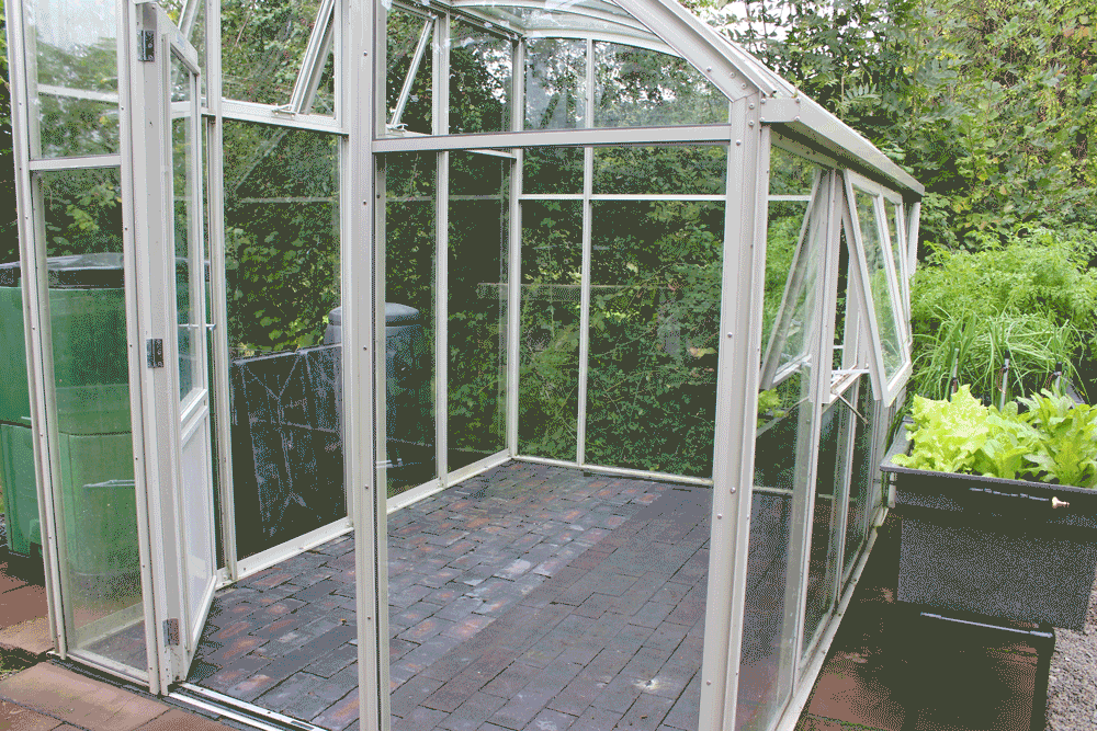 A greenhouse being installed with a self watering growing kit.